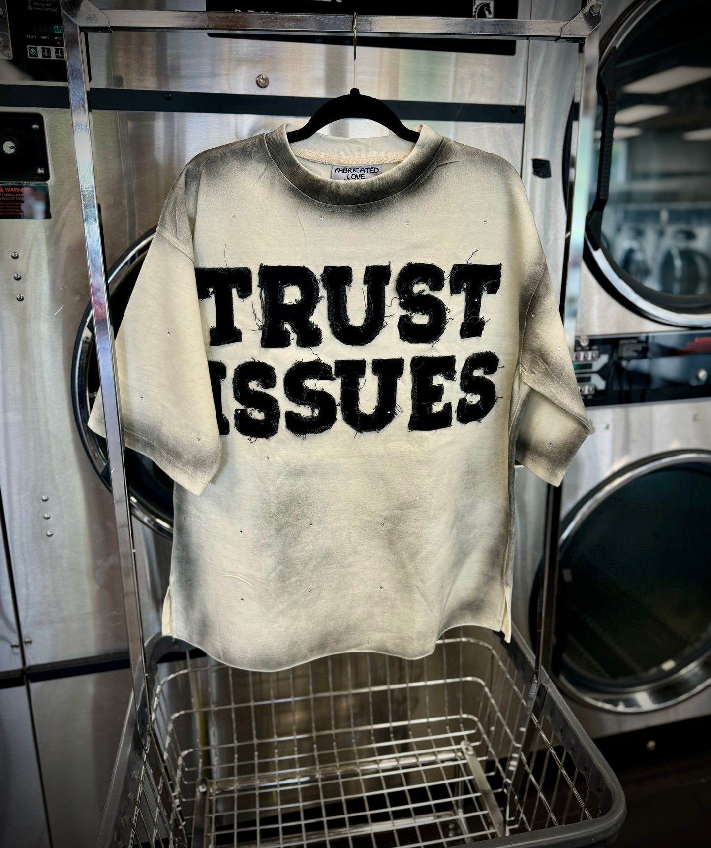 FABRICATED LOVE CREAM & BLACK “TRUST ISSUES” DROP SHOULD RHINESTONE TEE.