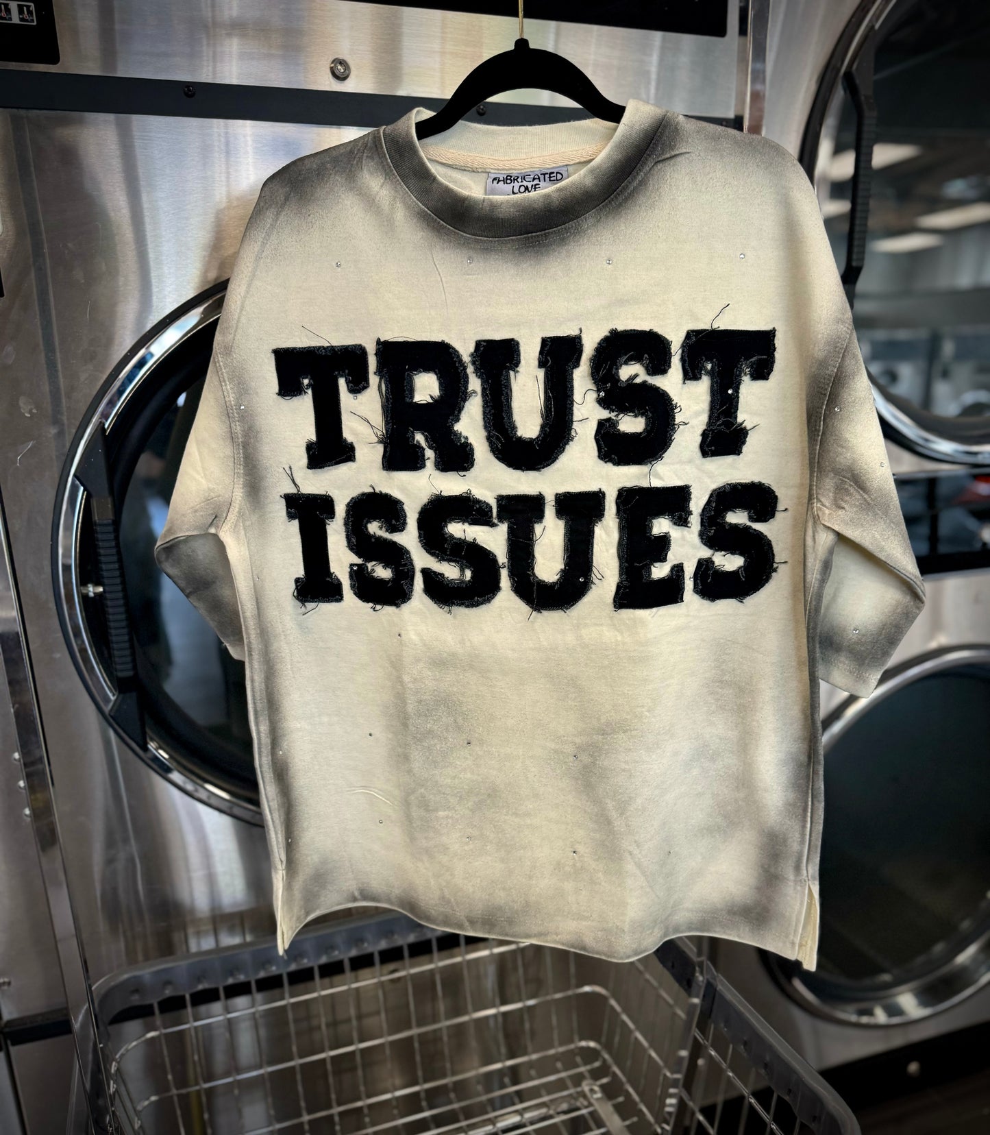 FABRICATED LOVE CREAM & BLACK “TRUST ISSUES” DROP SHOULD RHINESTONE TEE.